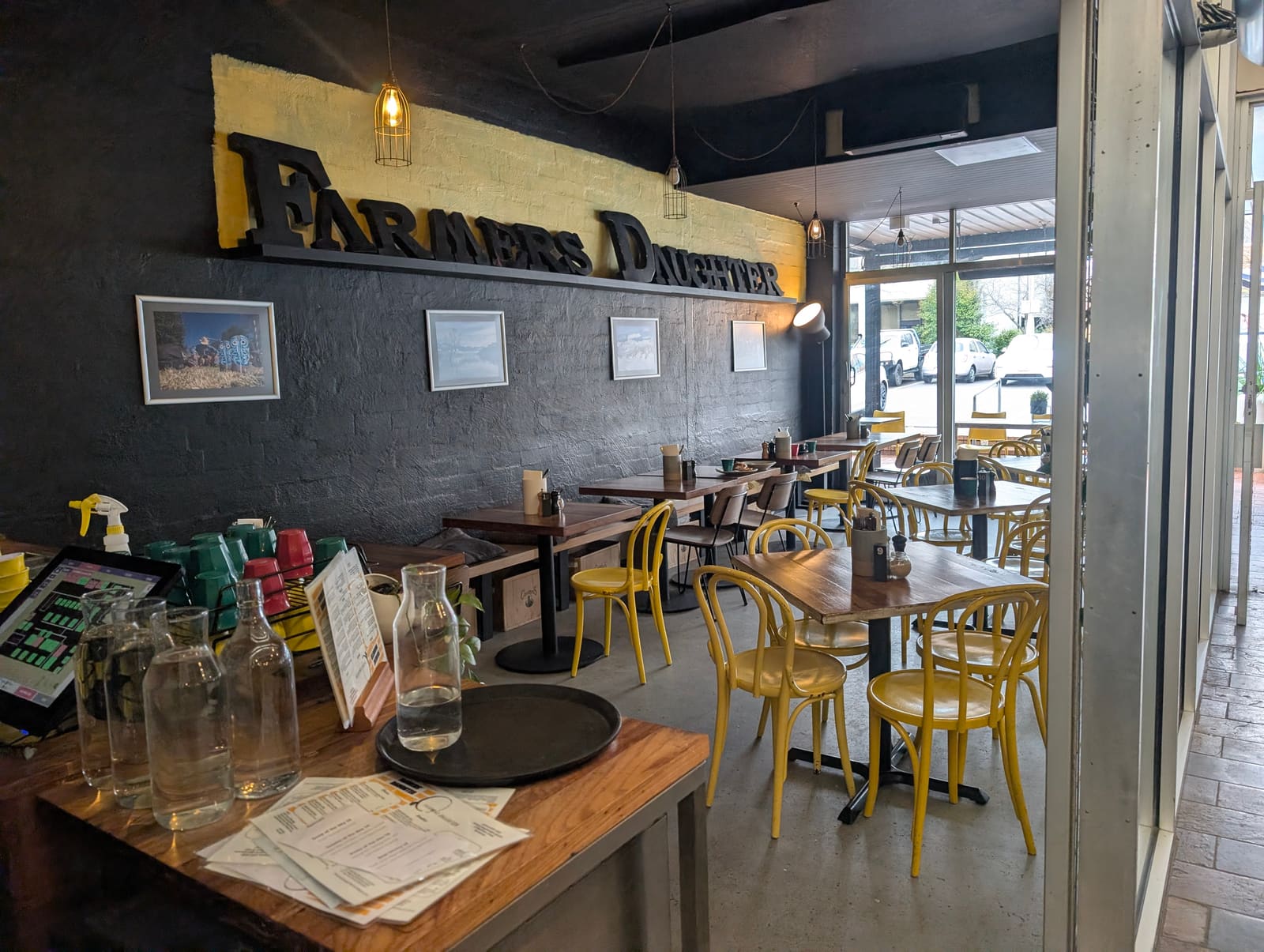 The Farmers Daughter dining room, with yellow bentwood chairs and the café’s bold sign